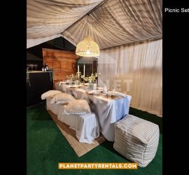 Picnic Event setup with Draped Tent, Pillows, Green Carpet, Tablecloths and Wooden Backdrop